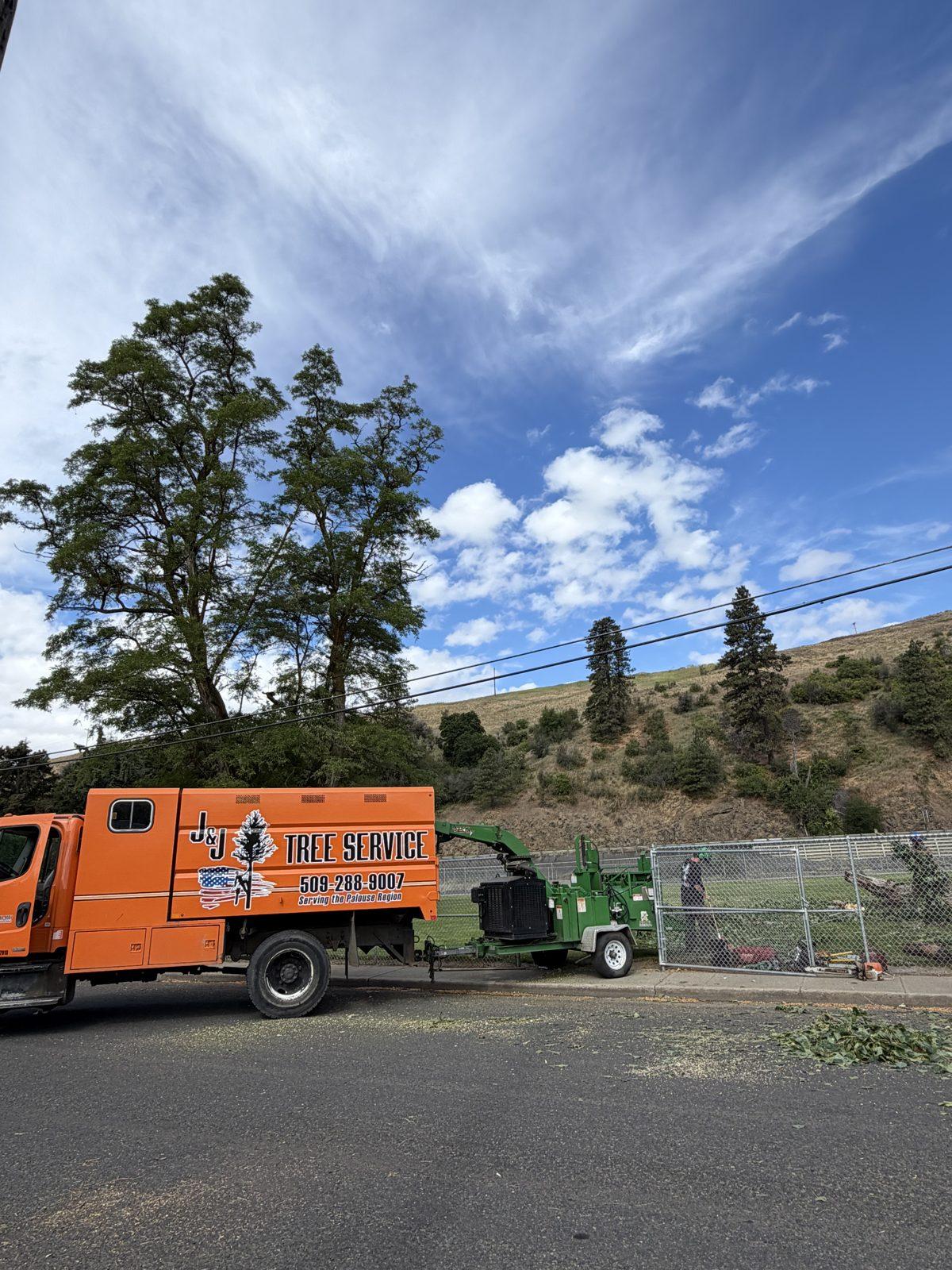 Orange J&J's Tree Service truck loaded with cleared tree debris